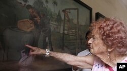 Audey Elliot of Adelaide, Australia, right, touches a painting depicting Khmer Rouge torture as she tours in the former Khmer Rouge's notorious S-21 prison now known as the Tuol Sleng genocide museum in Phnom Penh, file photo. 