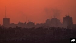 Destroyed buildings stand in the Gaza Strip as the sun sets, as seen from southern Israel on July 17, 2024.