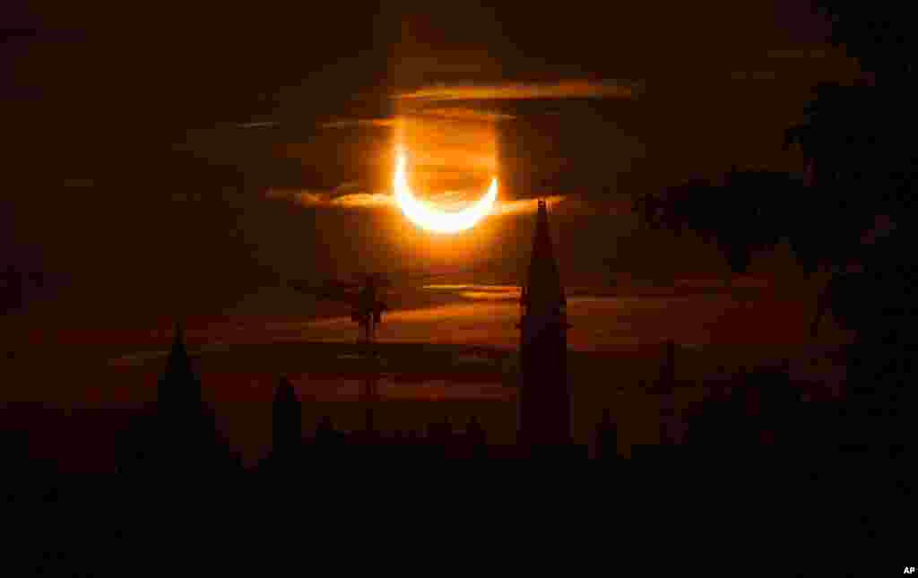 An annular solar eclipse rises over construction cranes and the Peace Tower on Parliament Hill in Ottawa, Canada.