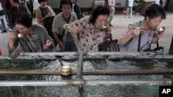 Elderly women rinse their mouths with holy water at a shrine in Tokyo, Japan on Sept. 29, 2012. 