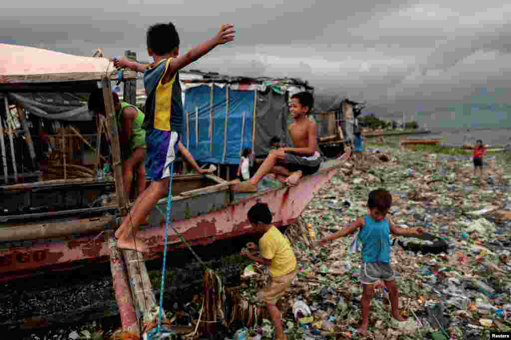 Children play on a boat docked on the garbage-filled shore of Baseco Beach in Tondo, Manila, Philippines.