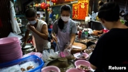 Adulwitch Tangsupmanee, 42, and Jirintat, son and daughter of Chanchai Tangsupmanee, who died at age 73 of the coronavirus disease (COVID-19) in July, prepare meals at their late father's food stall in Bangkok's Chinatown, Thailand, October 6, 2021. (REUTERS/Athit Perawongmetha)