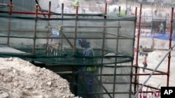 FILE - A foreign worker climbs scaffolding at the Al-Wakra Stadium that is under construction for the 2022 World Cup in Doha, Qatar, May 4, 2015.