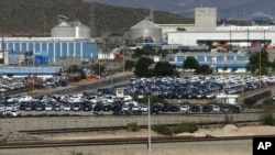 FILE - Cars sit at the General Motors plant in Ramos Arizpe, Mexico, Nov. 21, 2013. General Motors employs cheaper labor in Mexico, paying workers an average of about $10 an hour, compared to the $33 average autoworkers make in the U.S.