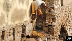 FILE - A low-caste sweeper cleans excreta flowing out of a public toilet at Ajmer, India.