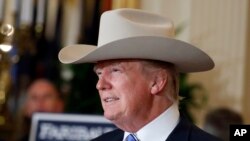 El presidente Donald Trump se prueba un sombrero de vaquero marca Stetson, fabricado en Texas, durante una exhibición en la Casa Blanca en el anuncio de la Semana de productos Hechos en EE.UU. Julio 17 de 2017.