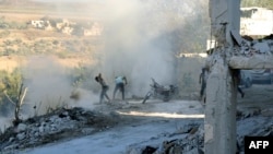 Syrians use dirt to put out a fire at the scene of a reported airstrike in the district of Jisr al-Shughur, in the Idlib province, Sept. 4, 2018.