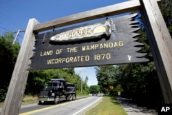 In this June 25, 2018 photo, a wooden sign advises motorists of the location of Mashpee Wampanoag Tribal lands in Massachusetts.