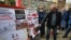 FILE - A man uses a slipper to slap a poster that shows a portrait of Belarusian President Alexander Lukashenko as people gather signatures in support of potential presidential candidates in upcoming presidential elections in Minsk, Belarus, May 24, 2020.