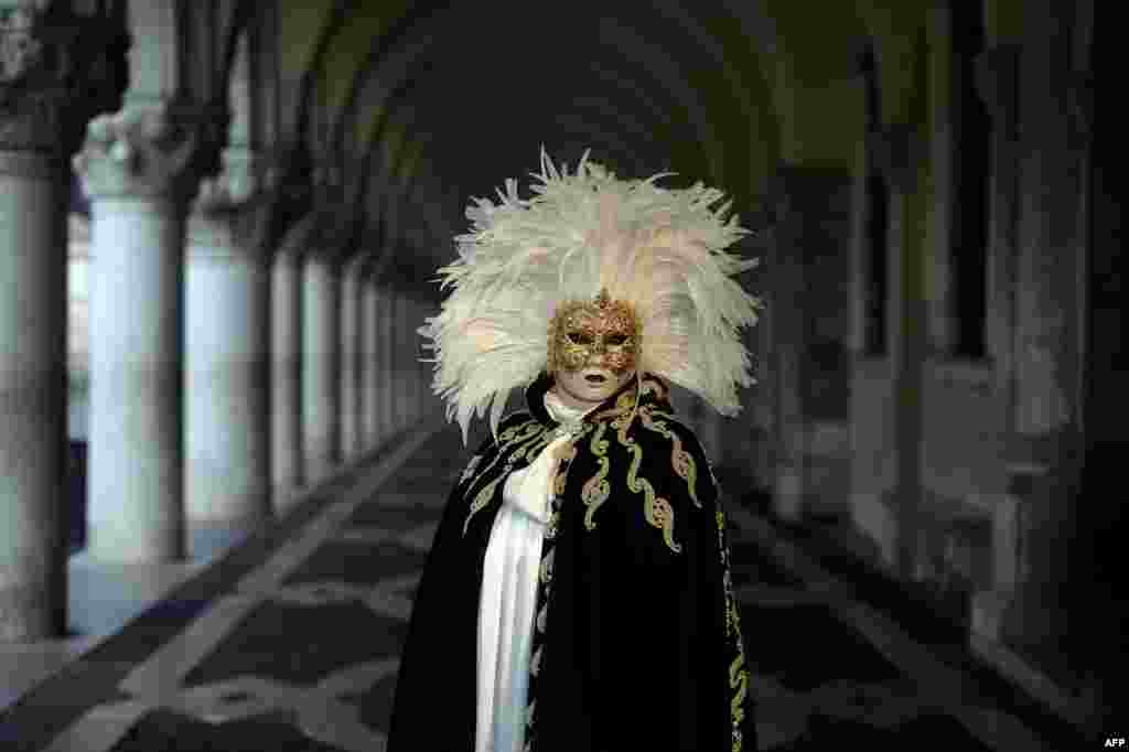 A masked reveler wearing a traditional carnival costume stands in St. Mark Square during Venice&#39;s Carnival, Italy.