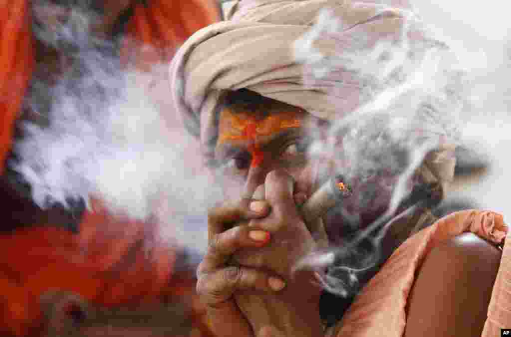 A Hindu holy man smokes as he waits to register for the annual pilgrimage to the Amarnath cave shrine in Jammu, India. Thousands of pilgrims annually visit the remote Himalayan shrine at 3,888 meters above sea level to worship an icy stalagmite representing Shiva, the Hindu god of destruction.