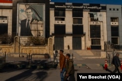 Aleppo residents walk by a police station that was stormed by HTS rebel fighters more than two weeks ago during the offensive that led to the fall of Bashar al-Assad’s regime.