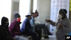 A medical worker addresses some of the first vaccine volunteers, at the Chris Hani Baragwanath hospital in Soweto, Johannesburg Wednesday, June 24, 2020.