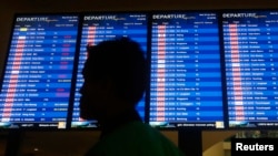 A man walks in front of a flight board at Kuala Lumpur International Airport 2 (KLIA2) in Sepang, Apr. 30, 2014. 