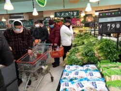 FILE - People wearing masks shop at a supermarket on the second day of the Chinese Lunar New Year, following the outbreak of a new coronavirus, in Wuhan, Hubei province, China, Jan. 26, 2020.