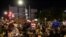 FILE - People watch as police arrest protesters for breaking a curfew during a solidarity rally calling for justice over the death of George Floyd, June 5, 2020, in the Brooklyn borough of New York. 