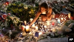 A woman lights candles at a new memorial in a gazebo in a seaside park on the famed Promenade des Anglais in Nice, southern France, July 18, 2016.