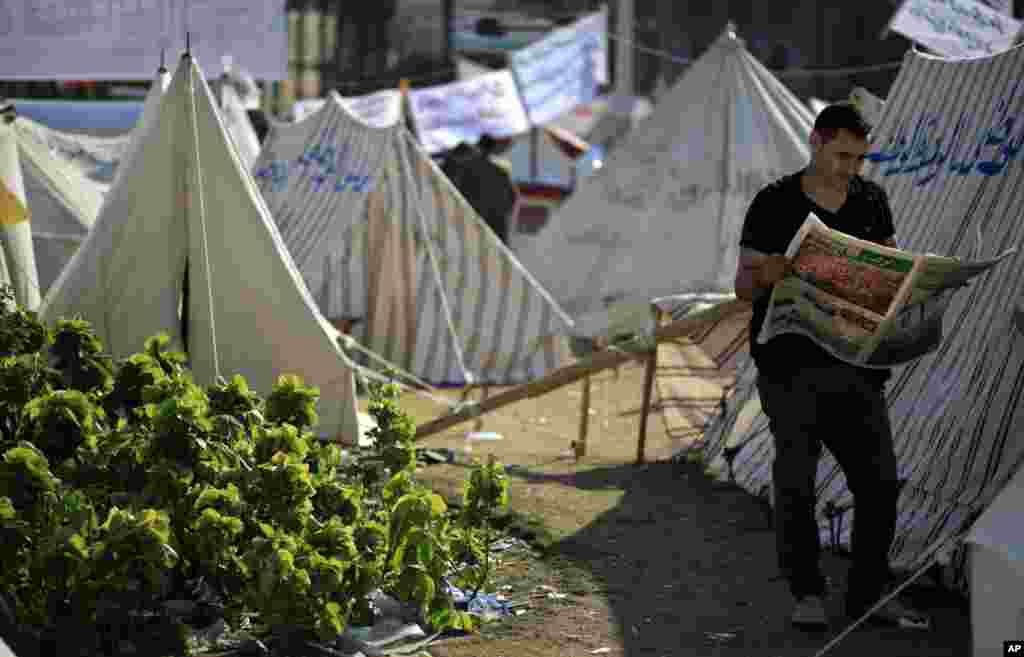 A protester reads the Wafd, a local newspaper next to tents occupied by protesters in Tahrir Square, in Cairo, Egypt, November 28, 2012.