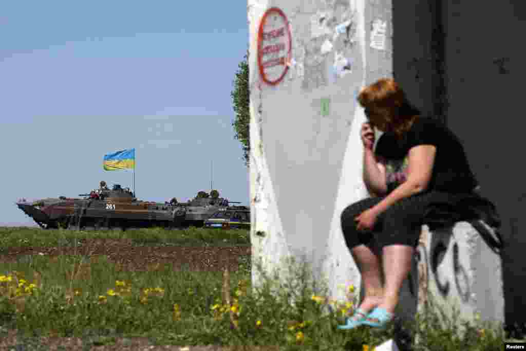 A woman looks at a Ukrainian armored personnel carrier at a checkpoint in Mariupol, May 7, 2014.