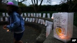 FILE - A young volunteer helps set up lights in paper bags decorated with messages for loved ones during an Out of the Darkness Walk event organized by the Cincinnati Chapter of the American Foundation for Suicide Prevention, Oct. 15, 2017, in Cincinnati. Hundreds of supporters gathered to draw attention to and raise funds for the prevention of suicide that ranks as the 10th leading cause of death in the United States overall according to the Centers for Disease Control and Prevention.