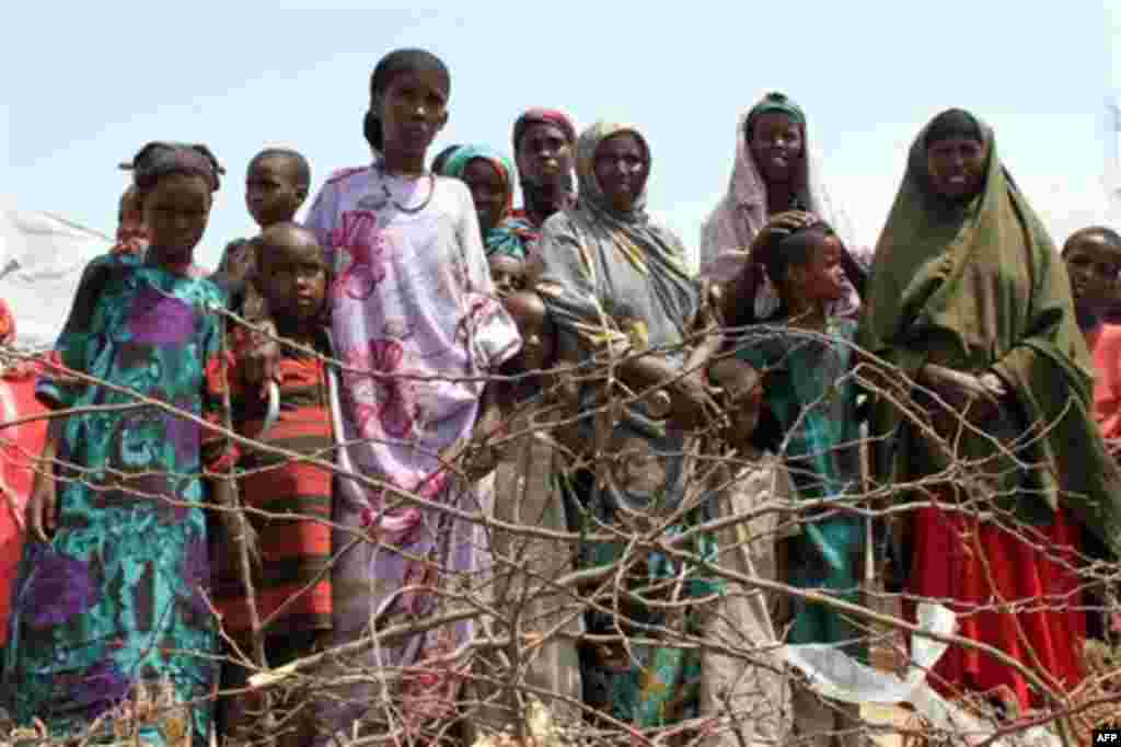 Women and children stand at the edge of an impromptu camp of internally displaced people that has sprung up near the airport, Mogadishu, Wednesday, July 27, 2011. The camp has very few men because al-Shabab would not let them leave the south-central regio