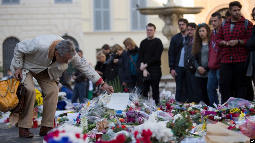 Warga memberi penghormatan kepada para korban serangan teror maut di Paris di depan Kedutaan Besar Perancis di Roma (16/11). (AP/Andrew Medichini)