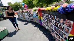 A visitor looks over a display with the photos and names of the 49 victims that died at the Pulse nightclub memorial June 11, 2021, in Orlando, Fla.