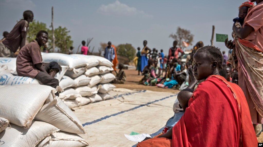 FILE - People wait to receive food at a World Vision food distribution site in Malualkuel in the Northern Bahr el Ghazal region of South Sudan, April 5, 2017.