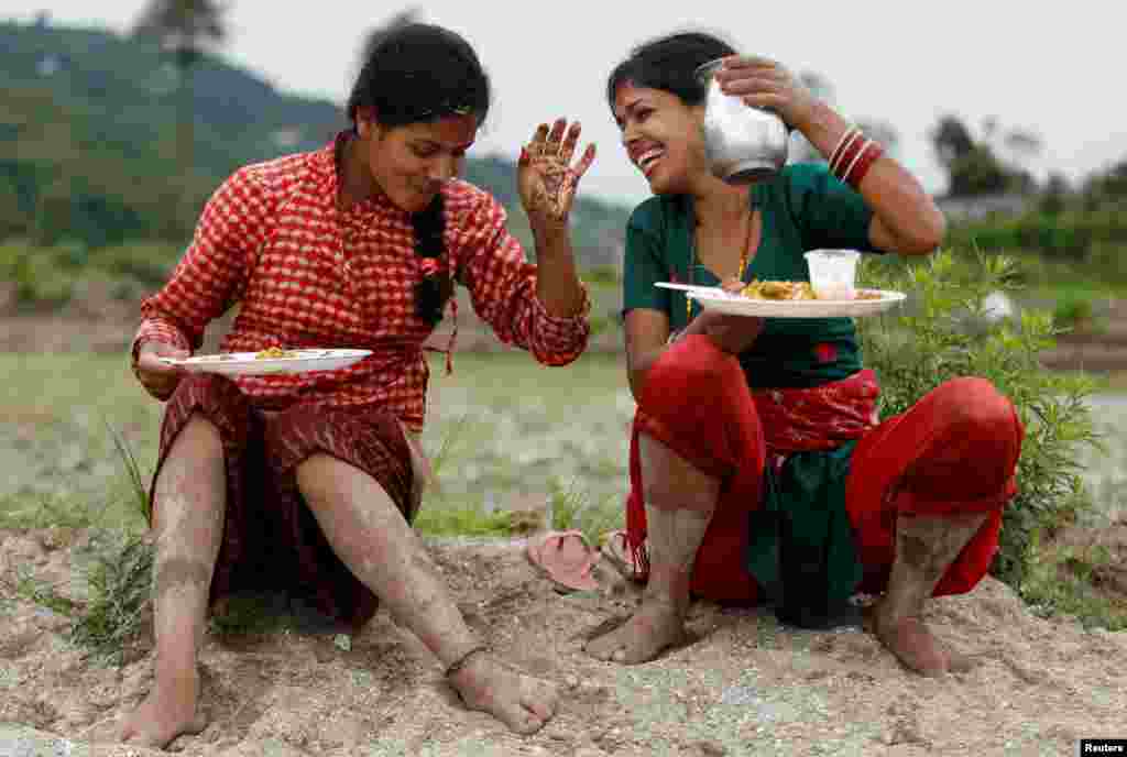 Farmers take a break for lunch while celebrating National Paddy Day, also called Asar Pandra, that marks the start of rice crop planting as monsoon season arrives, in Kathmandu, Nepal.