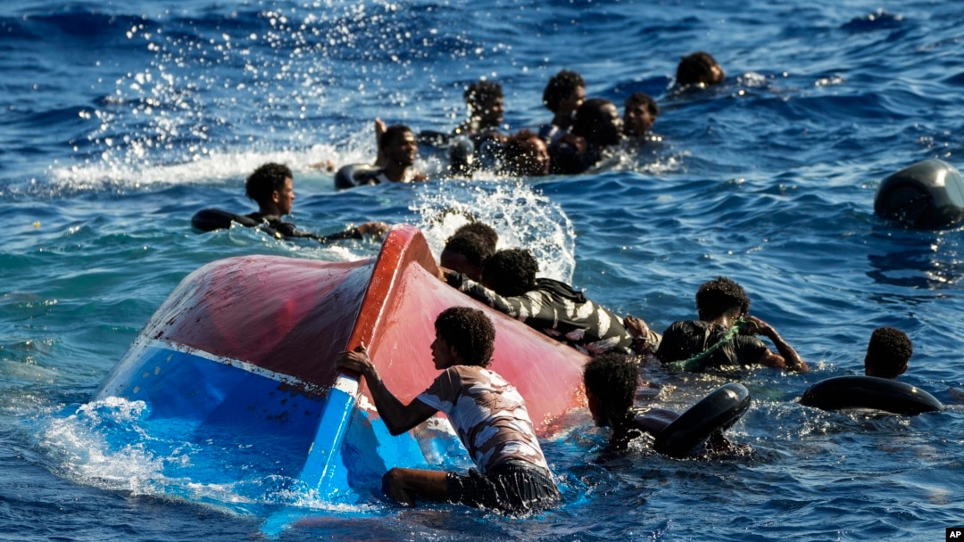 FILE - Migrants swim next to their overturned wooden boat during a rescue operation by Spanish NGO Open Arms at south of the Italian Lampedusa island in the Mediterranean Sea, Aug. 11, 2022. 