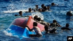 FILE - Migrants swim next to their overturned wooden boat during a rescue operation by Spanish NGO Open Arms at south of the Italian Lampedusa island at the Mediterranean sea, Aug. 11, 2022.