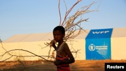 FILE - A refugee walks past a World Food Program tent at Um-Rakoba camp, in al-Qadarif state, Sudan, Nov. 23, 2020.