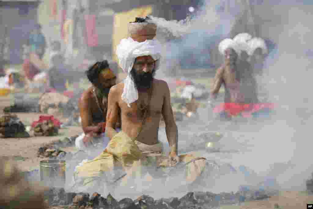 Orang-orang suci Hindu membakar kotoran sapi kering sementara mereka melakukan ritual keagamaan di Sangam, pada festival Magh Mela di Allahabad, India.