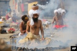 Hindu holy men burn dried cow dung cakes as they perform a ritual at Sangam, confluence of rivers Ganges and Yamuna on "Basant Panchami" day at the annual traditional fair of Magh Mela in Allahabad, India, Monday, Jan. 22, 2018.