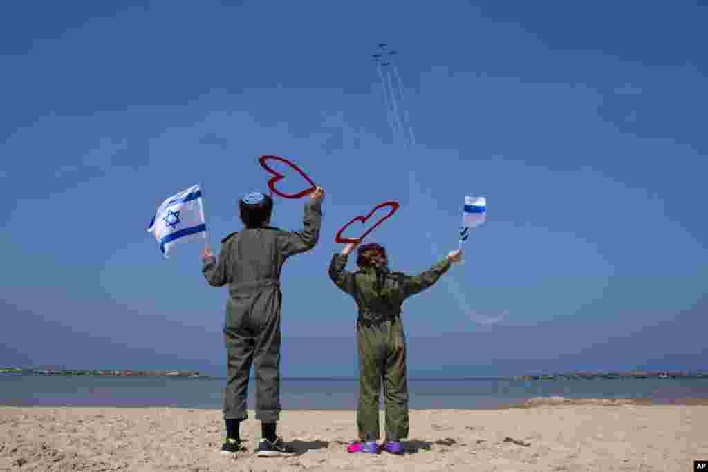 دو کودک اسرائیلی در لباس خلبانی پرچم اسرائیل را برای جت های جنگی این کشور تکان می دهند. هفتادمین سالگرد تشکیل کشور اسرائیل است.