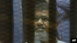 FILE - Egypt's ousted president Mohammed Morsi is seen sitting in a cage inside a makeshift courtroom at Egypt’s national police academy in Cairo, Egypt, Apr. 21, 2015. 
