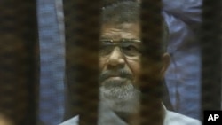 Tổng thống Ai Cập bị lật đổ Mohammed Morsi ngồi trong một lồng kính cách âm bên trong phòng xử án tại học viện cảnh sát quốc gia ở Cairo, ngày 21/4/2015.