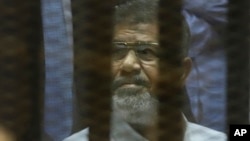 Mantan Presiden Mesir Mohammed Morsi duduk di balik pembatas kedap suara di ruang persidangan Akademi Polisi Nasional di Kairo, 21 April 2015. 