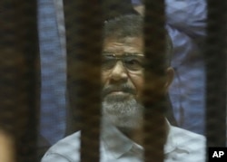 FILE - Egypt's ousted Islamist President Mohammed Morsi sits in a soundproof glass cage inside a makeshift courtroom at Egypt’s national police academy in Cairo, Egypt, April 21, 2015.
