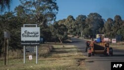 Des travailleurs passent devant une enseigne de la mine d'or Sibanye-Stillwater Driefontein près de Carletonville, près de Johannesburg, le 5 mai 2018 (AFP PHOTO / MUJAHID SAFODIEN).