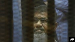 FILE - Egypt's ousted Islamist President Mohammed Morsi sits in a soundproof glass cage inside a makeshift courtroom at Egypt’s national police academy in Cairo, April 21, 2015. 