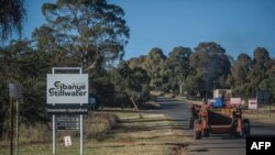 Des travailleurs passent devant une enseigne de la mine d'or Sibanye-Stillwater Driefontein près de Carletonville, près de Johannesburg, le 5 mai 2018.