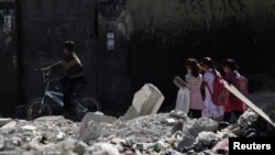 Children go to school on a damaged street in Damascus.