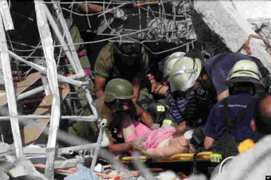 Rescue workers help an injured woman in Concepcion, 500 km south of Santiago, 27 Feb 2010