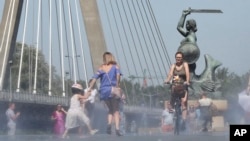 FILE - People cool off by the Vistula River during a heatwave in Warsaw, Poland, June 30, 2019.