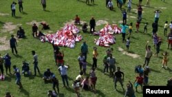 Penduduk desa yang terdampak bencana gempa bumi di desa Lindu di selatan Palu, Sulawesi Tengah, melambaikan tangan seusai mendapatkan bantuan yang dijatuhkan dari helikopter militer Indonesia, 7 Oktober 2018. (Foto: dok).