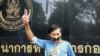 Thai journalist Pravit Rojanaphruk flashes a V-sign as he stands with his mouth taped outside a military base in Bangkok where he had been summoned by the junta, May 25, 2014.