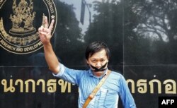 FILE - Thai journalist Pravit Rojanaphruk flashes a V-sign as he stands with his mouth taped outside a military base in Bangkok where he had been summoned by the junta, May 25, 2014.