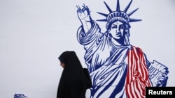 FILE - A woman walks in front of new anti-U.S. murals on the walls of the former U.S. embassy in Tehran, Iran, Nov. 2, 2019. 