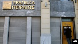 FILE - A man uses an ATM of Piraeus Bank in central Athens. The ESM approved a 2.72 billion euro ($2.88 billion) disbursement to recapitalize the ailing bank.